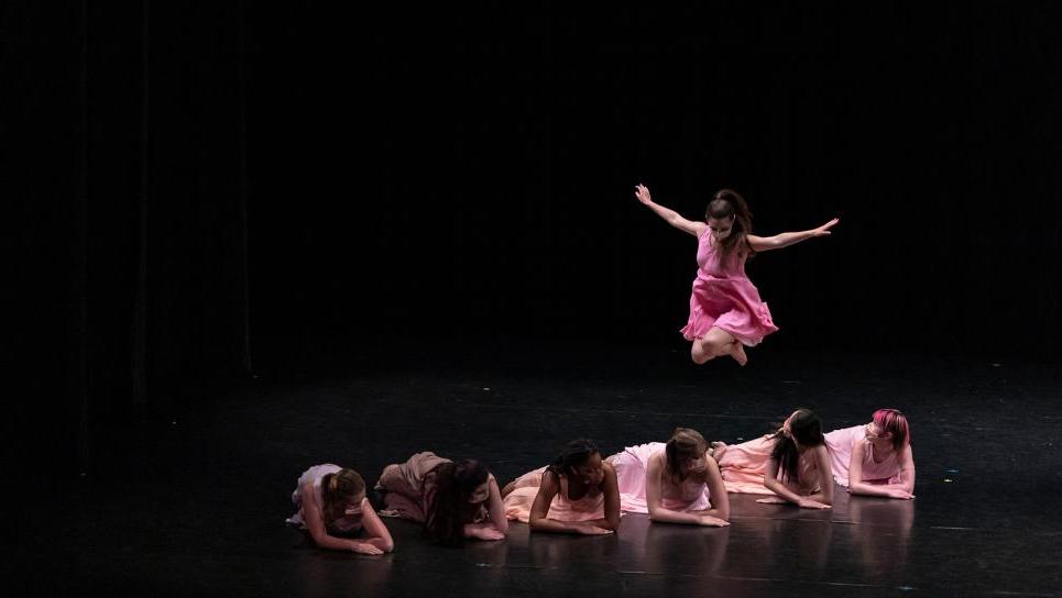 Image of dancers on stage; one dancer is jumping